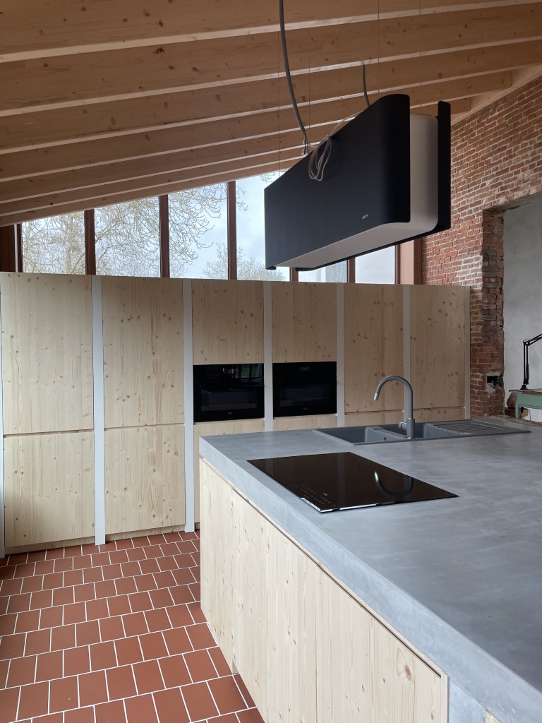 een keuken met betonnen werkblad en een eilanddampkap van Novy